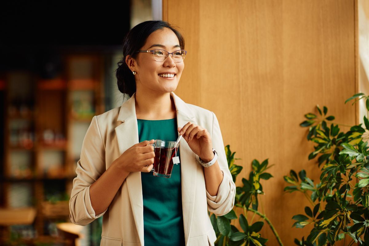 Does Tea have Dental Health Benefits Woman holding tea cup smiling in dental office, representing tea's dental health benefits.