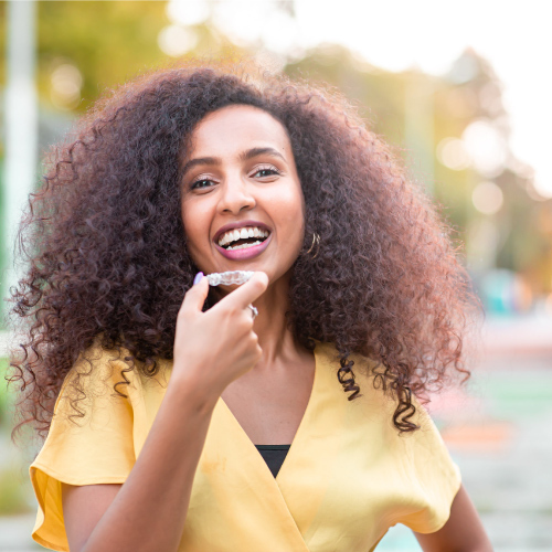 Beautiful smiling African woman is holding Invisalign