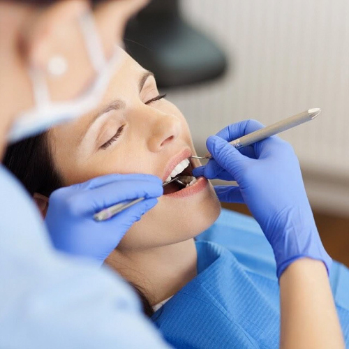 Closeup of female dentist examining mid adult patient's mouth in clinic