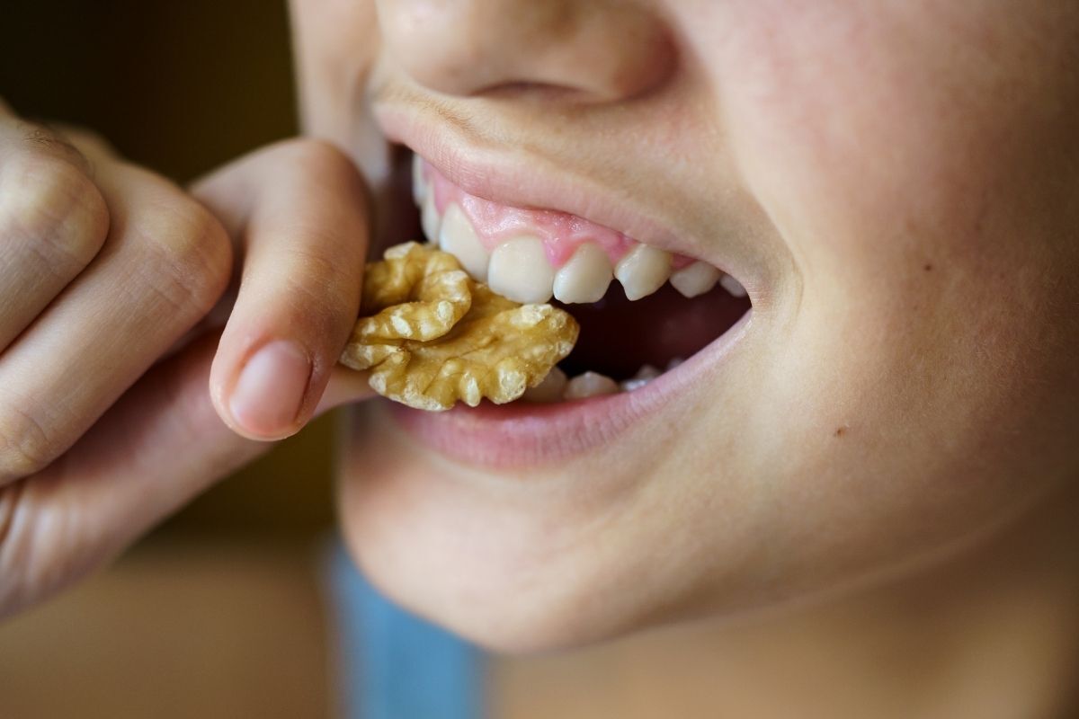 Tooth Hurt When You Bite Down Child biting walnut, demonstrating tooth pain from biting down on hard foods.